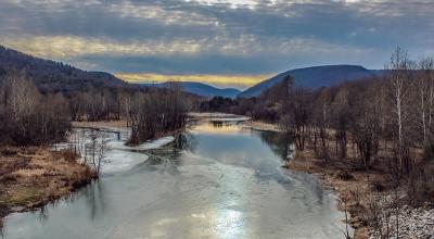 sunset over a stream with mountains in the background